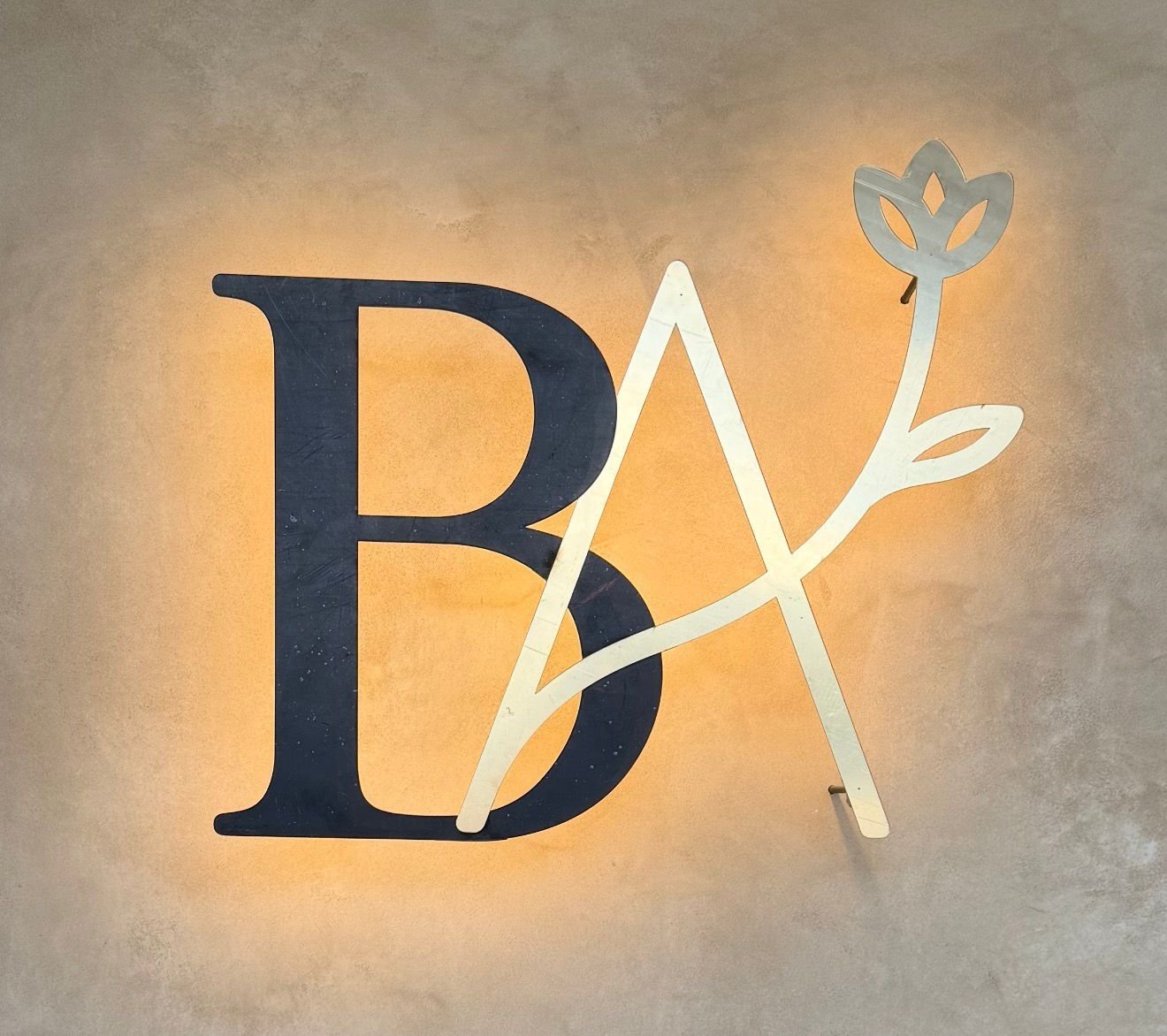 Logotipo BA iluminado sobre muro de microcemento